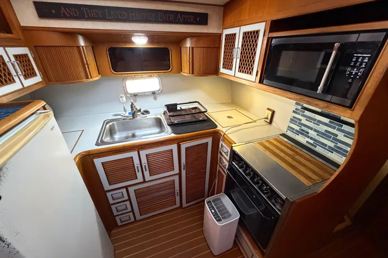 Slide: The Image of 1987 Hi-Star 55 Yacht Fisherman kitchen with wood cabinetry, sink, stove, and microwave. - 33