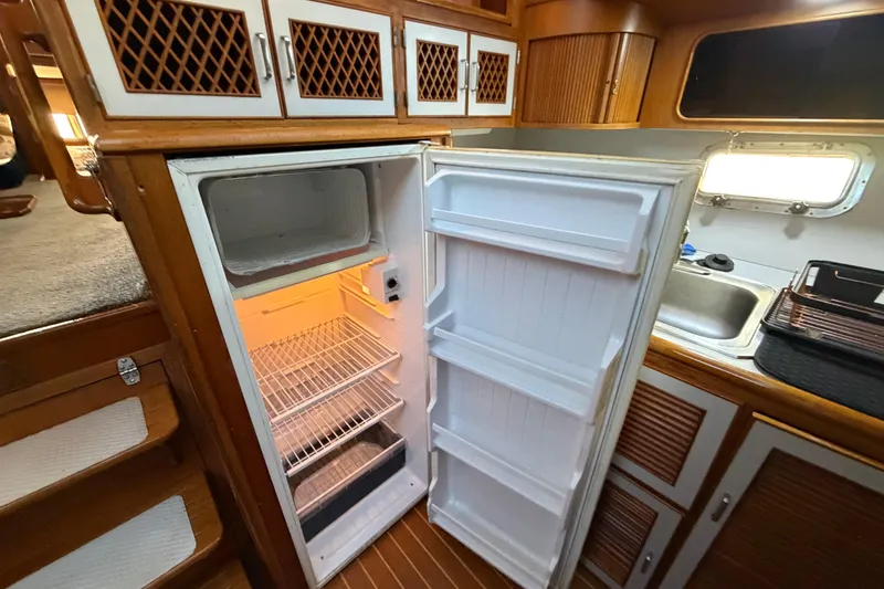 Slide: The Image of Open refrigerator in 1987 Hi-Star 55 Yacht Fisherman kitchen, wooden cabinets, and sink visible. - 34