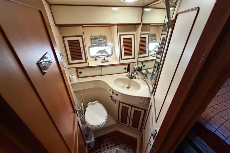 Slide: The Image of 1987 Hi-Star 55 Yacht Fisherman bathroom with sink, toilet, and wooden cabinetry. - 47