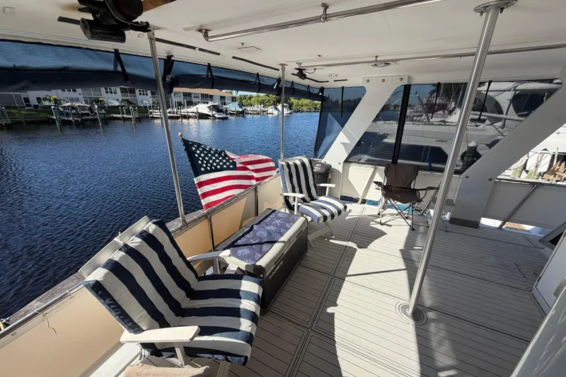 Slide: The Image of 1987 Hi-Star 55 Yacht Fisherman deck with striped chairs and American flag, docked by the water. - 5