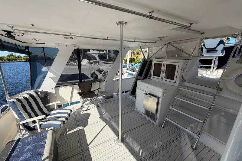 Slide: The Image of 1987 Hi-Star 55 Yacht Fisherman interior with seating, storage, and stairs, docked by the water. - 6