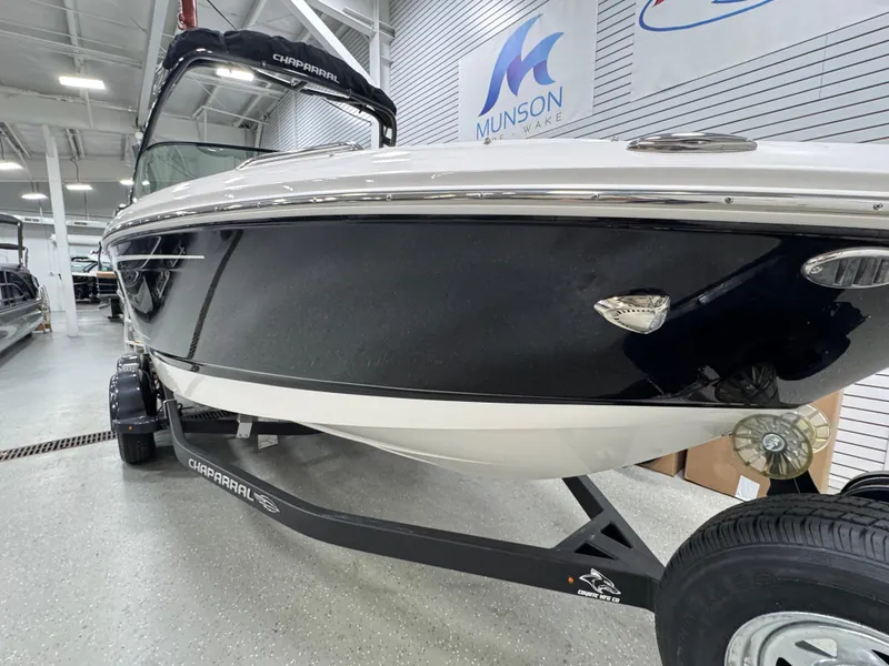 Slide: The Image of 2025 Chaparral 21 SSi boat in showroom, black and white exterior, on trailer. - 2