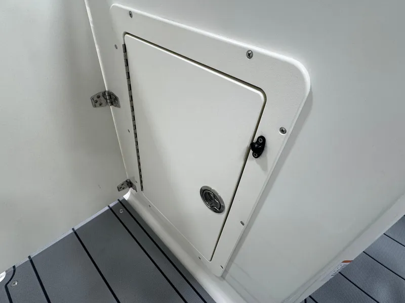 Slide: The Image of 2025 Chaparral 21 SSi boat storage compartment with sleek white finish and secure latch. - 22