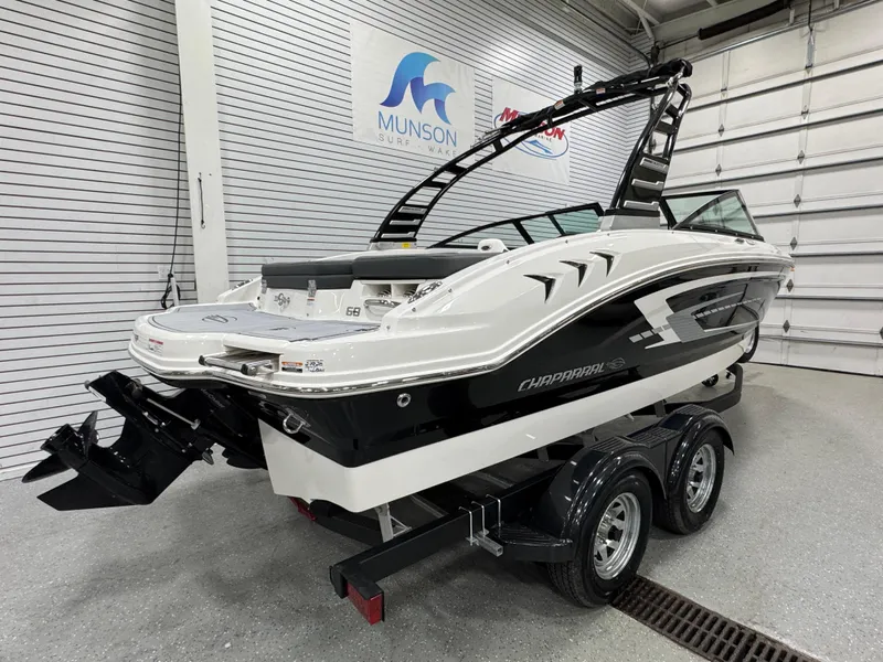 Slide: The Image of 2025 Chaparral 21 SSi boat on trailer in showroom, sleek design, black and white color. - 3