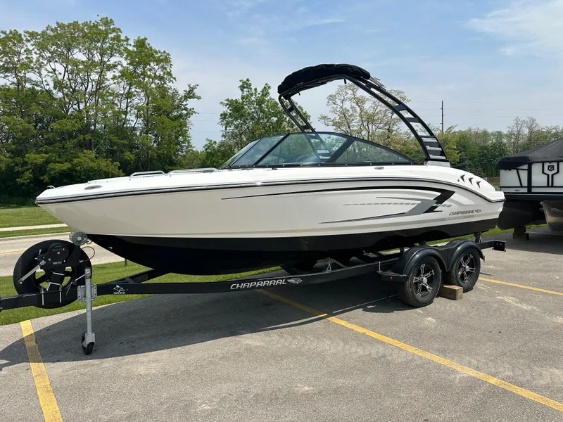The Image of 2025 Chaparral 21 SSi boat on trailer, parked outdoors, surrounded by trees. - 0