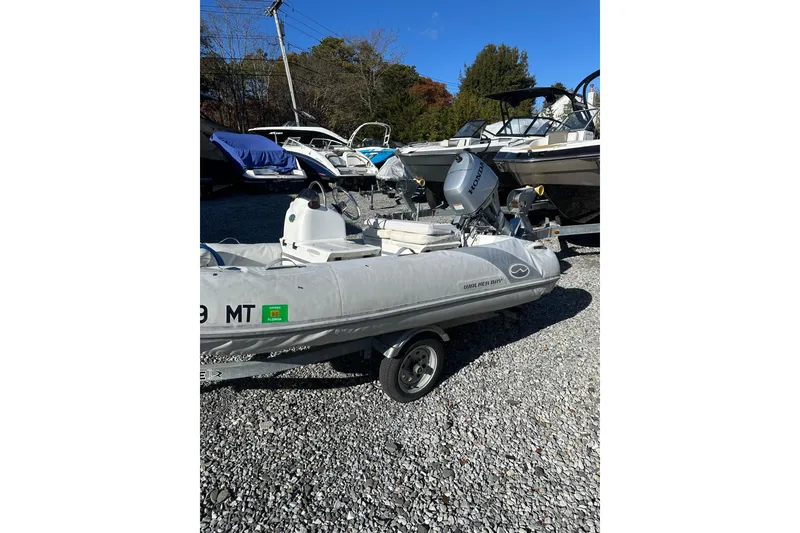 Slide: The Image of 2016 Walker Bay 325 ST inflatable boat with Honda outboard motor on gravel lot. - 3