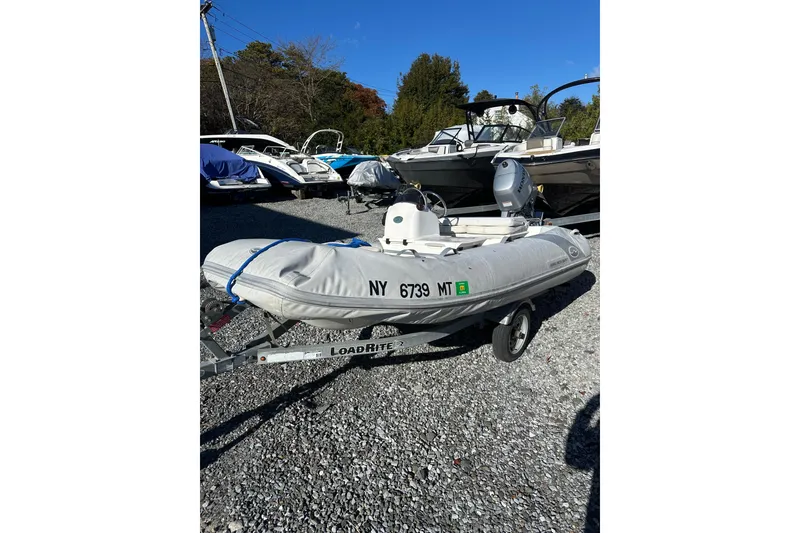 Slide: The Image of 2016 Walker Bay 325 ST inflatable boat on LoadRite trailer, parked on gravel. - 5