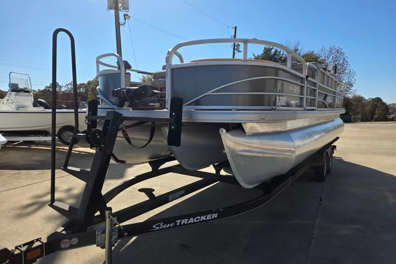 Slide: The Image of 2019 Sun Tracker Fishin' Barge 22 XP3 pontoon boat on trailer, outdoor setting. - 2