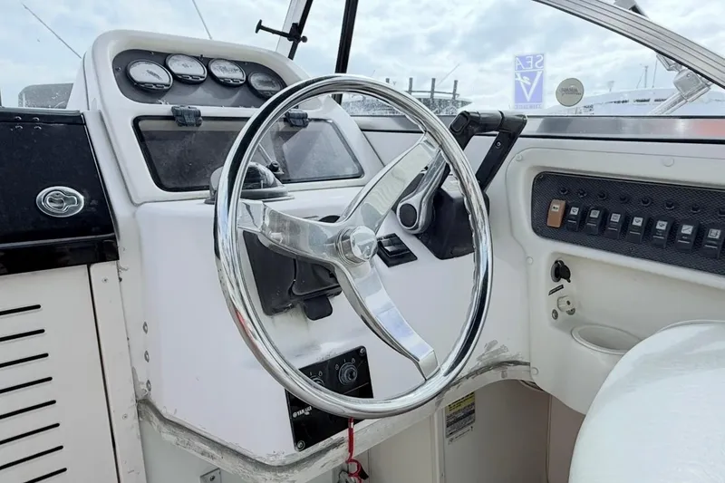 Slide: The Image of 2005 Grady-White Journey 258 boat dashboard with steering wheel and control panel. - 13