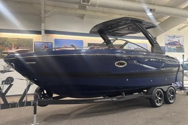 The Image of 2026 Chaparral 6 SSX boat on display in showroom, sleek design, dark blue exterior. - 0