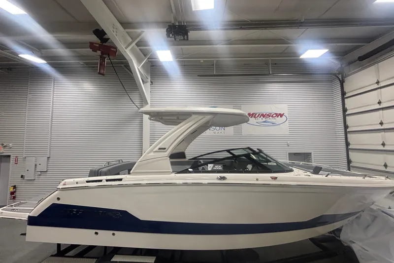 Slide: The Image of 2026 Chaparral 8 SSX boat in showroom, side view, white and blue design. - 3