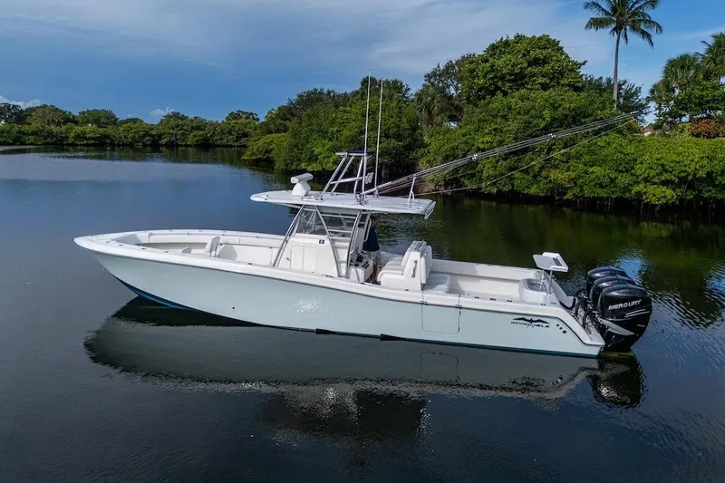 The Image of 2016 Invincible 39 Open Fisherman boat on calm water, surrounded by lush greenery. - 0