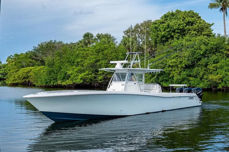 Slide: The Image of 2016 Invincible 39 Open Fisherman boat on calm water, surrounded by lush greenery. - 30