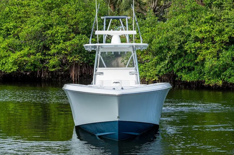 Slide: The Image of 2016 Invincible 39 Open Fisherman boat on calm water, surrounded by lush greenery. - 31