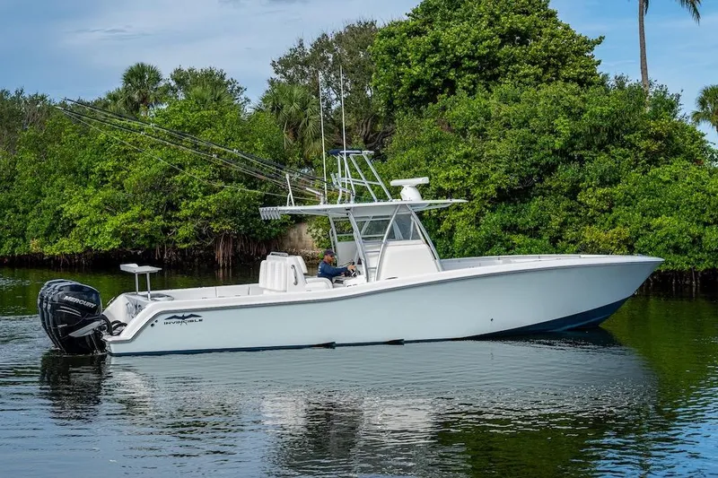 Slide: The Image of 2016 Invincible 39 Open Fisherman boat on calm water, surrounded by lush greenery. - 32