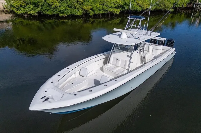 Slide: The Image of 2016 Invincible 39 Open Fisherman boat on calm water, surrounded by lush greenery. - 6