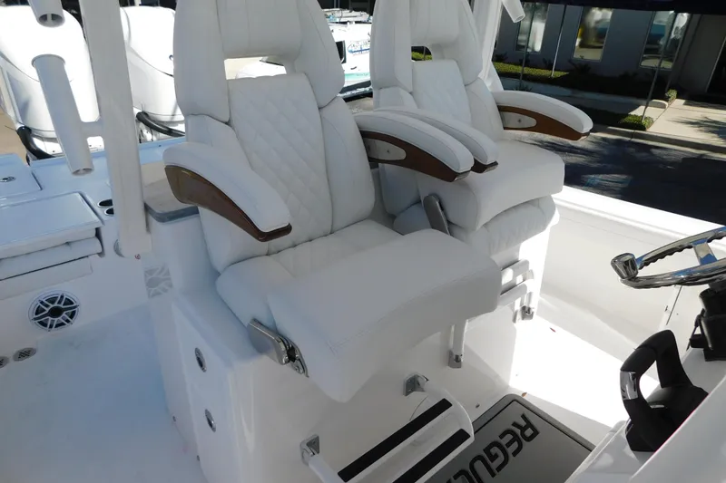 Slide: The Image of Luxury seating on 2026 Regulator 30XO boat, featuring white quilted upholstery and wooden armrests. - 19