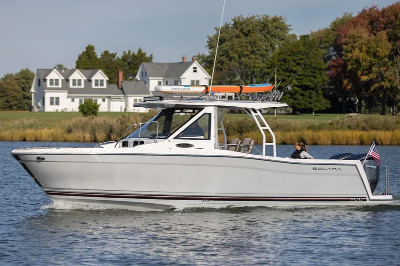 Slide: The Image of Manufacturer Provided Image: 2025 Solara S-310 CW boat cruising on a serene lake near waterfront homes. - 6