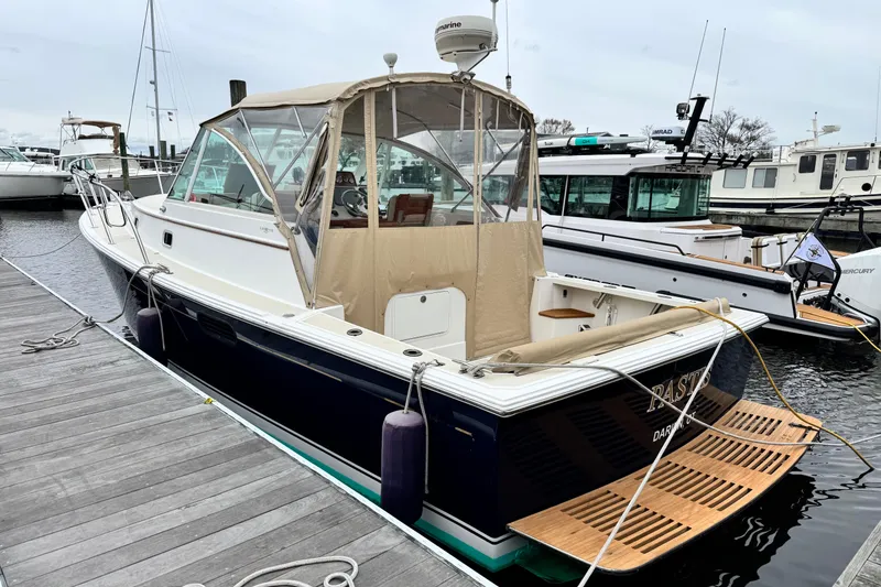 The Image of 2005 Hunt SurfHunter boat docked at marina, featuring tan canopy and wooden deck. - 0