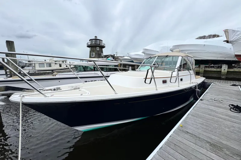Slide: The Image of 2005 Hunt SurfHunter boat docked at marina with lighthouse in background. - 2