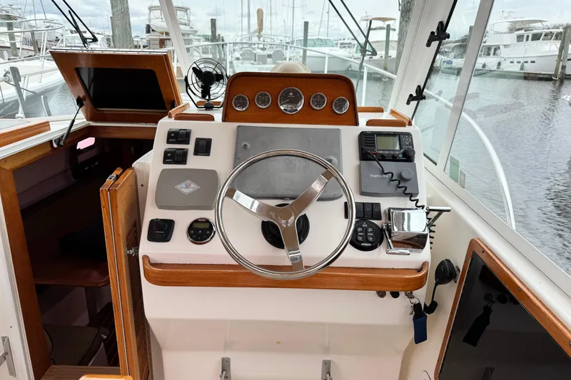 Slide: The Image of 2005 Hunt SurfHunter boat helm with steering wheel and navigation controls at marina. - 3