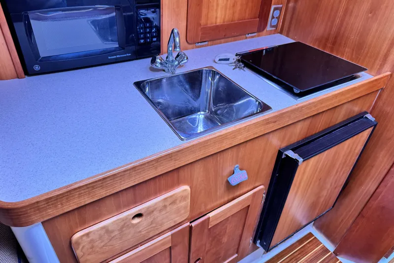 Slide: The Image of Compact kitchen area in a 2005 Hunt SurfHunter boat with sink, microwave, and stove. - 6