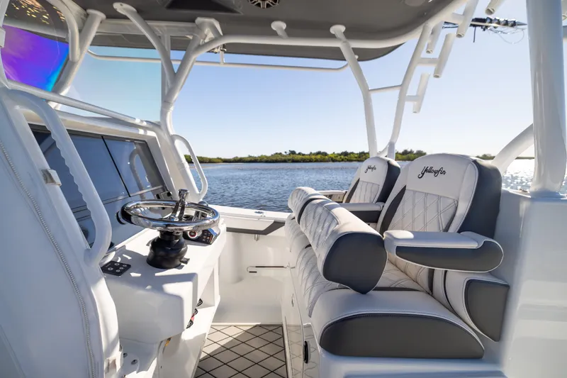Slide: The Image of 2023 Yellowfin 36 Offshore boat interior with luxurious seating and steering wheel, overlooking serene water. - 37