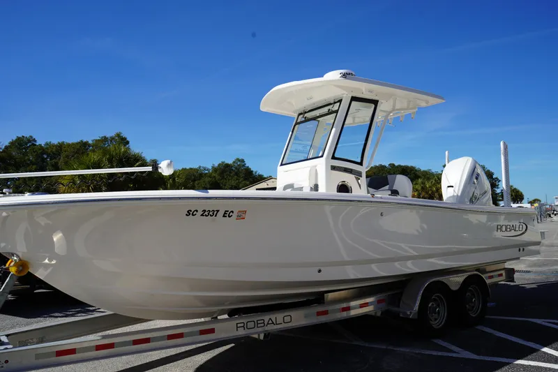 Slide: The Image of 2023 Robalo 266 Cayman boat on trailer under clear blue sky. - 2