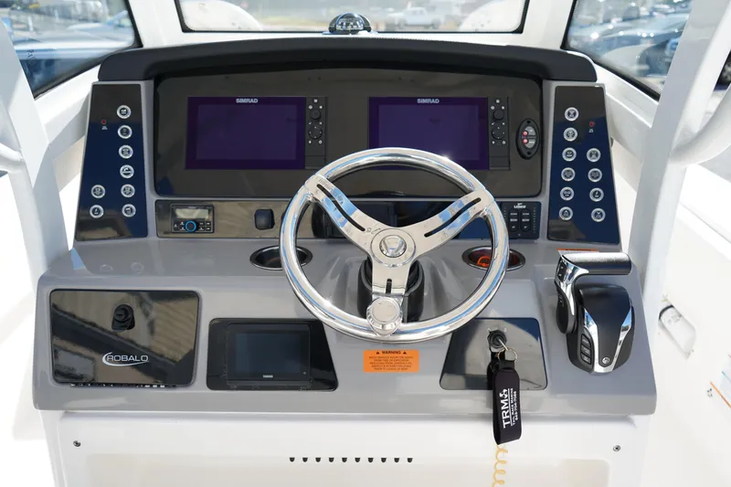 Slide: The Image of 2023 Robalo 266 Cayman boat dashboard with steering wheel and navigation controls. - 24