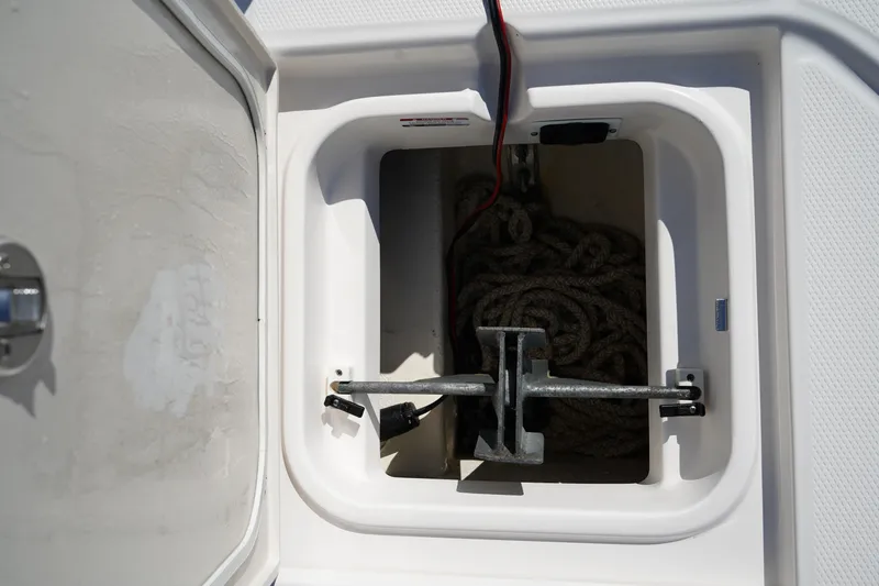 Slide: The Image of Anchor storage compartment on 2023 Robalo 266 Cayman boat, featuring coiled rope and metal anchor. - 42