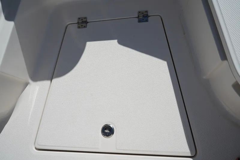 Slide: The Image of 2023 Robalo 266 Cayman boat storage compartment with textured lid and metal latch. - 59