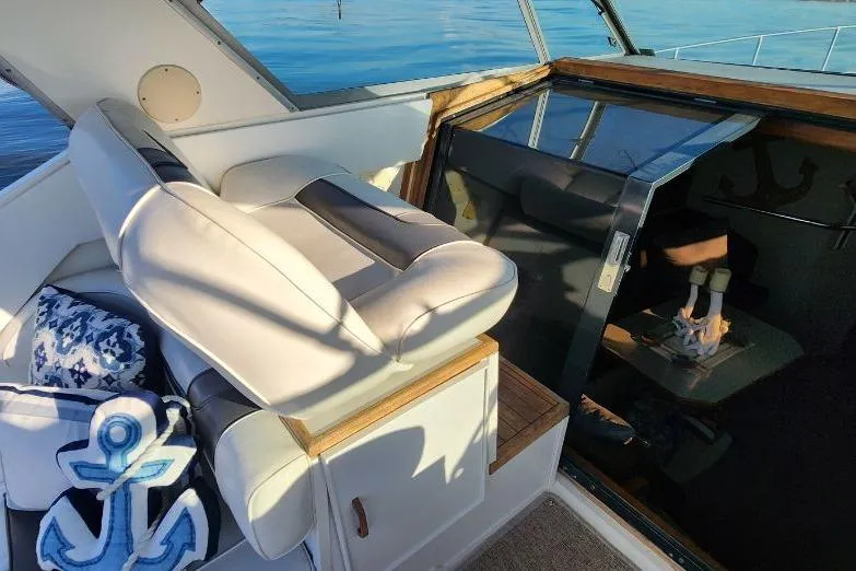 Slide: The Image of 1988 Sea Ray 390 Express Cruiser helm with leather seat and scenic water view. - 10