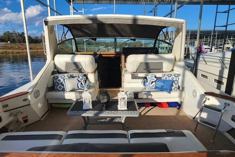 Slide: The Image of 1988 Sea Ray 390 Express Cruiser docked, featuring a spacious seating area with nautical decor. - 4