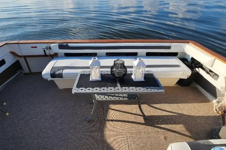 Slide: The Image of 1988 Sea Ray 390 Express Cruiser interior with plush seating and nautical decor on a sunny day. - 8