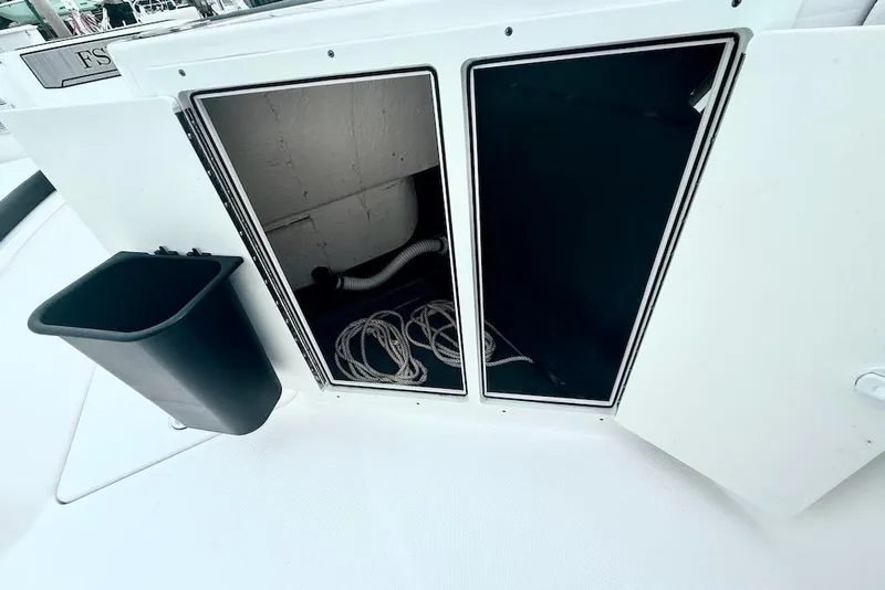 Slide: The Image of 2024 Yamaha Boats 222 FSH Sport E storage compartment with ropes and a black container. - 13
