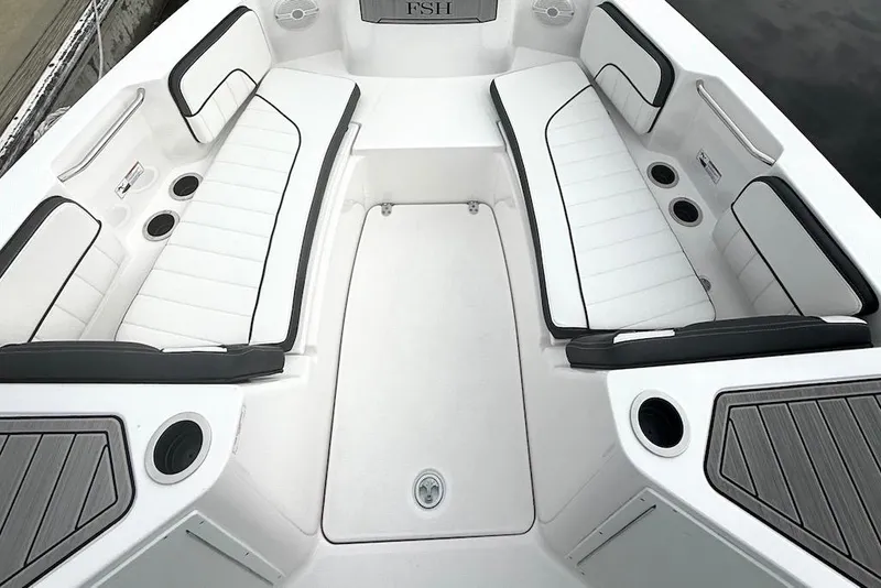 Slide: The Image of 2024 Yamaha Boats 222 FSH Sport E interior with white cushioned seating and cup holders. - 15