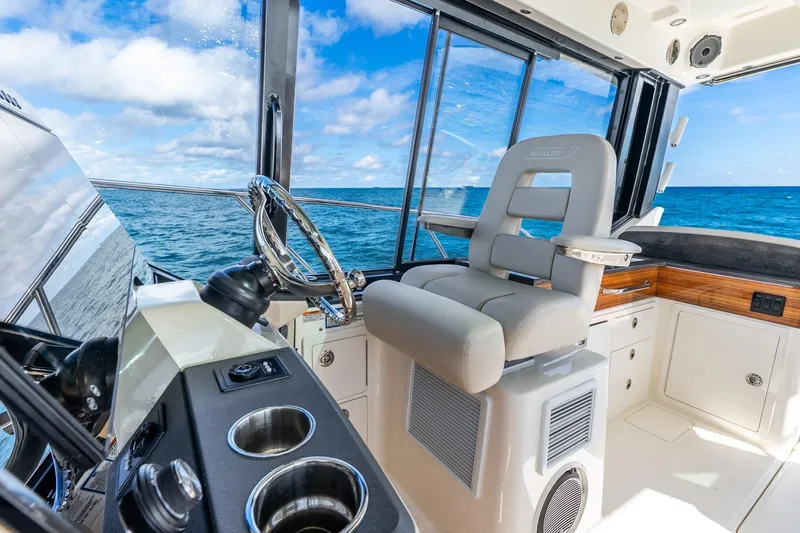 Slide: The Image of 2024 Boston Whaler 405 Conquest helm with ocean view, featuring luxurious seating and controls. - 16