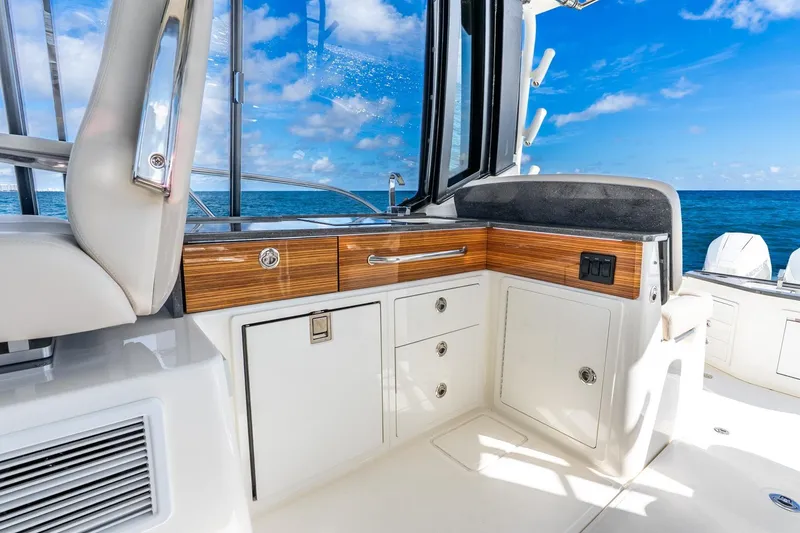 Slide: The Image of 2024 Boston Whaler 405 Conquest interior with ocean view, featuring sleek cabinetry and seating. - 22