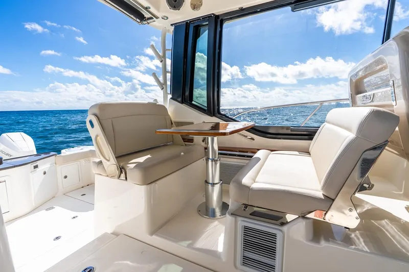 Slide: The Image of 2024 Boston Whaler 405 Conquest interior with ocean view, featuring comfortable seating and table. - 24