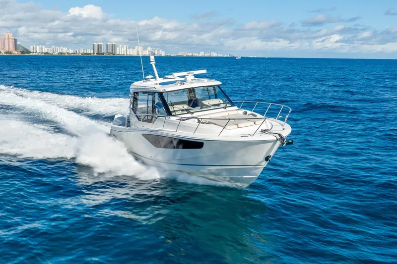 Slide: The Image of 2024 Boston Whaler 405 Conquest cruising on blue ocean near city skyline. - 5