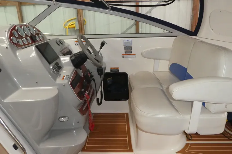 Slide: The Image of 2007 Bayliner 325 boat interior with steering wheel, dashboard, and cushioned seating. - 12
