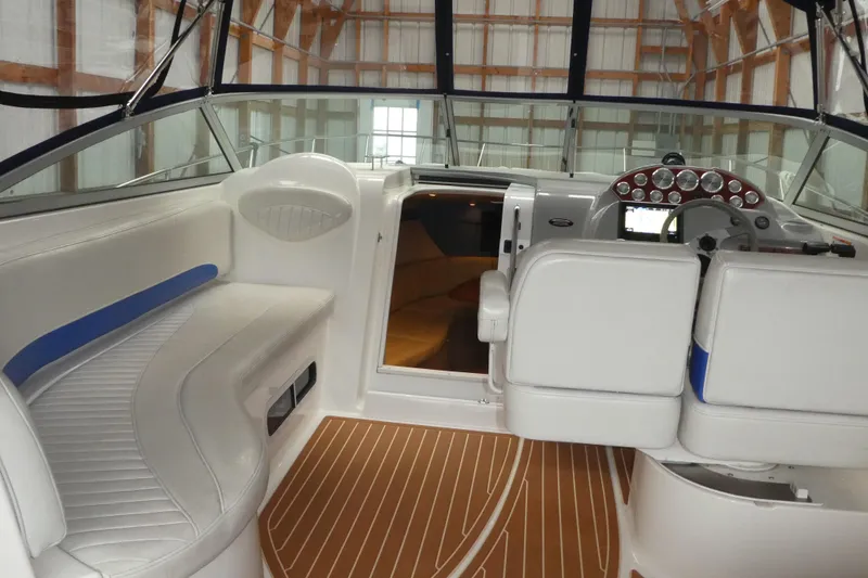 Slide: The Image of 2007 Bayliner 325 boat interior with white seating and wood-patterned flooring. - 16