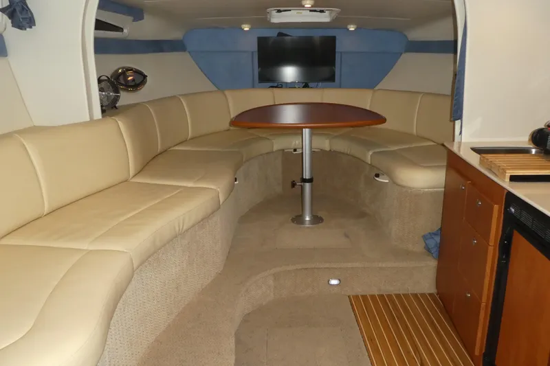 Slide: The Image of 2007 Bayliner 325 interior with beige seating, wooden table, and kitchenette. - 18