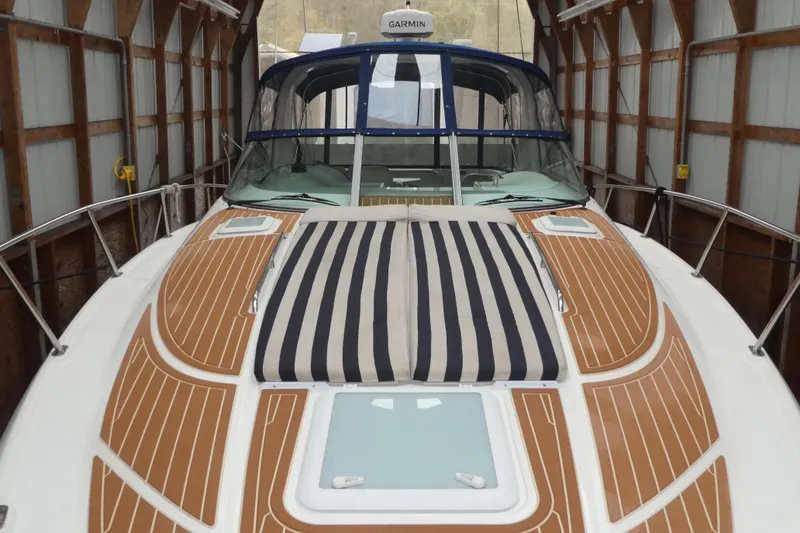 Slide: The Image of 2007 Bayliner 325 boat with striped sun pad, docked in a covered boathouse. - 2