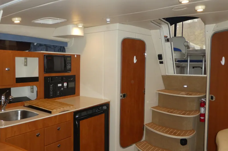 Slide: The Image of Interior of a 2007 Bayliner 325 boat featuring a kitchenette and stairs to the deck. - 29