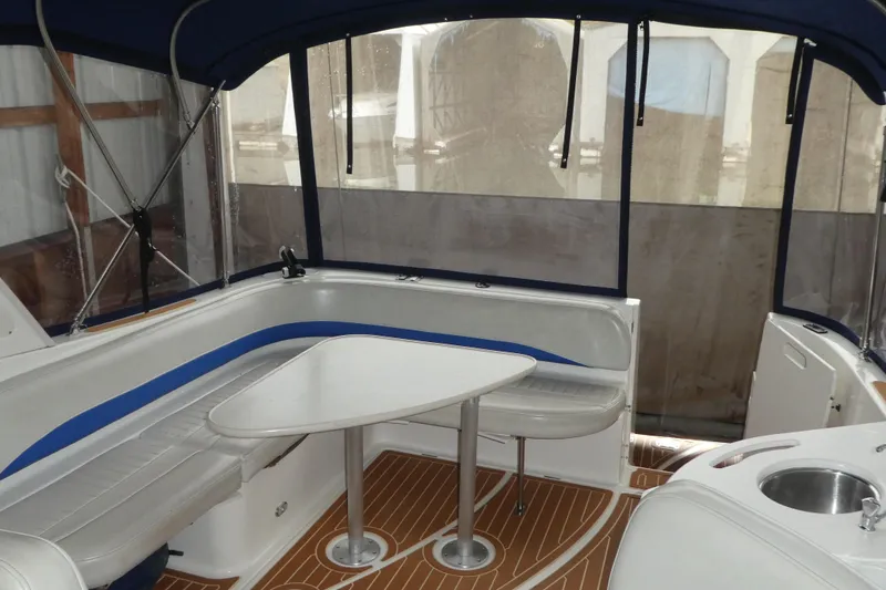 Slide: The Image of 2007 Bayliner 325 boat interior with seating, table, and wood-patterned flooring. - 7