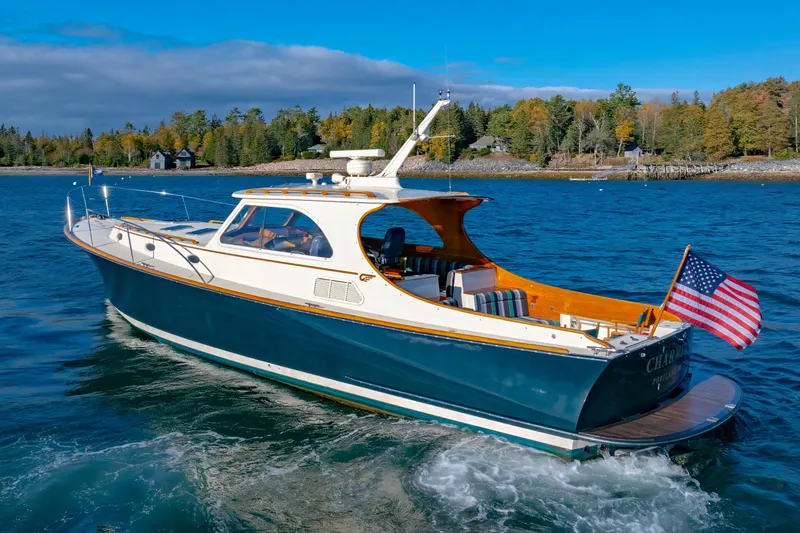 Slide: The Image of 1999 Hinckley Talaria 44 Express yacht cruising on a scenic lake with American flag. - 13