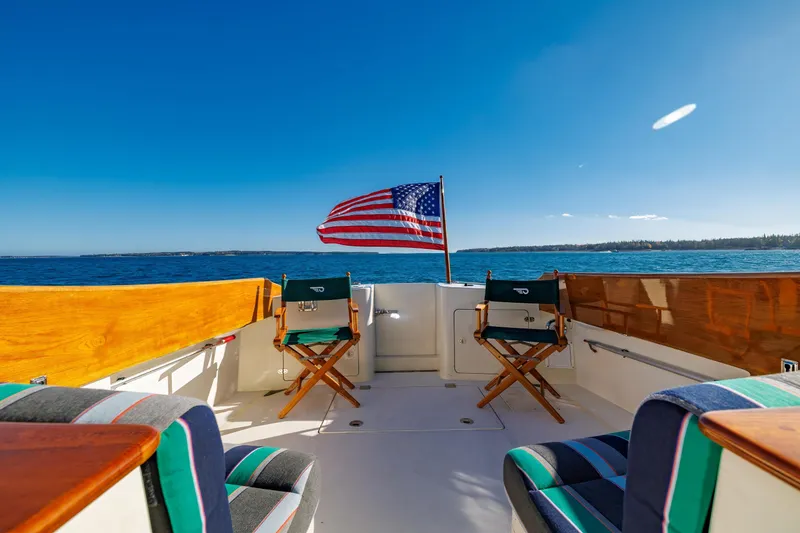 Slide: The Image of 1999 Hinckley Talaria 44 Express yacht deck with American flag, ocean view, and seating. - 18