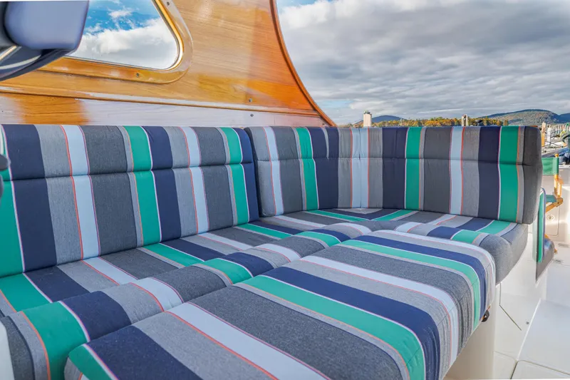 Slide: The Image of Striped seating on 1999 Hinckley Talaria 44 Express yacht, with wooden accents and scenic backdrop. - 21