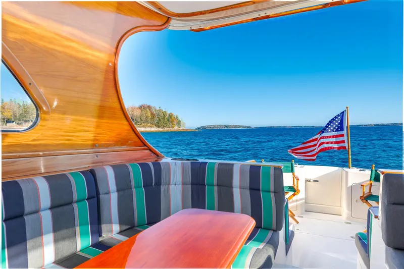 Slide: The Image of Hinckley Talaria 44 Express 1999 yacht interior with striped seating, wooden accents, and ocean view. - 24